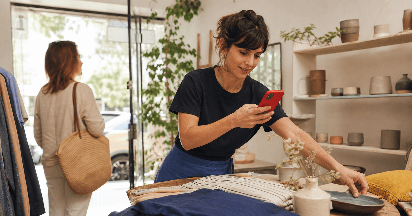 Comerciante atendiendo su tienda mientras prepara contenido para redes sociales