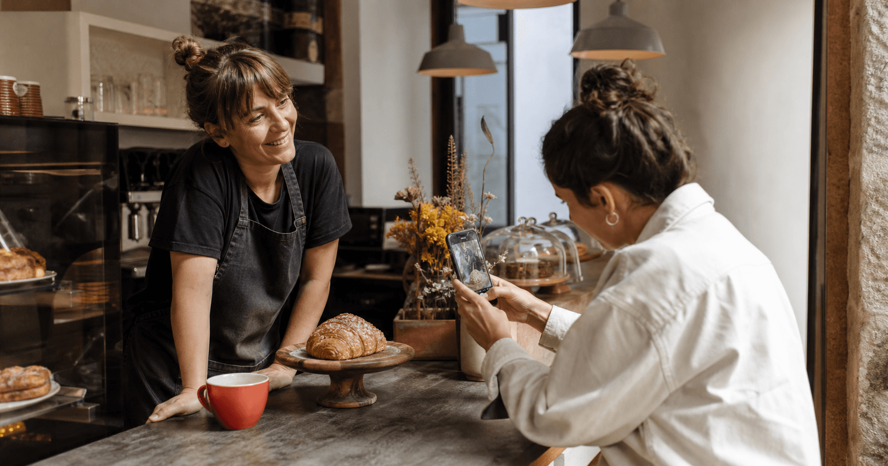 Creadora local fotografiando un producto en una pequeña cafetería